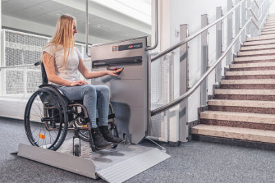 Stair Riser Lift in grey with a female wheelchair user using it.