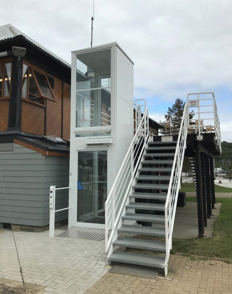 White external platform lift next to an exterior stair case.