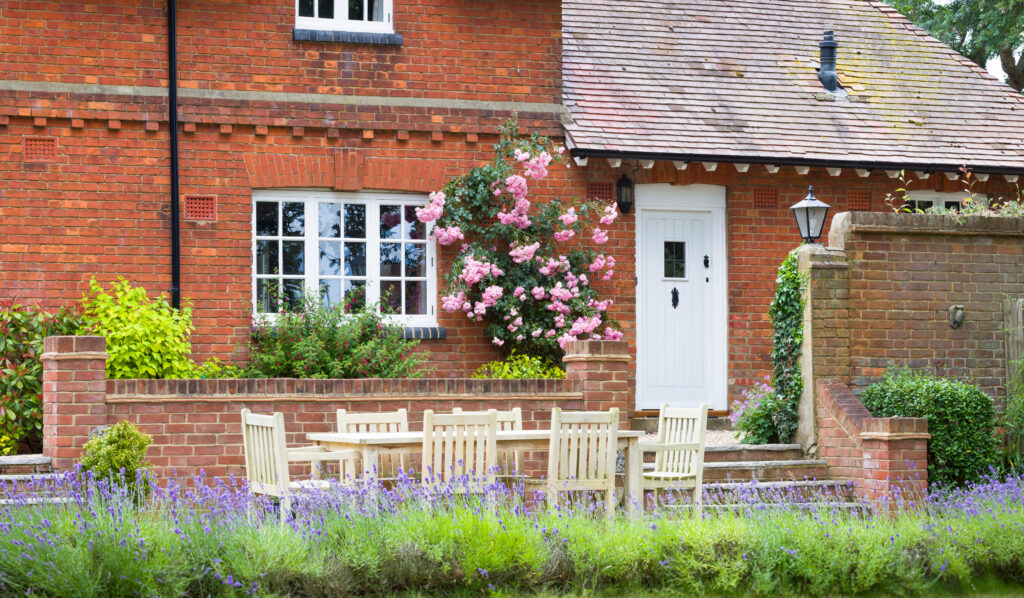 Exterior of large UK home. Country house and garden with wooden patio furniture